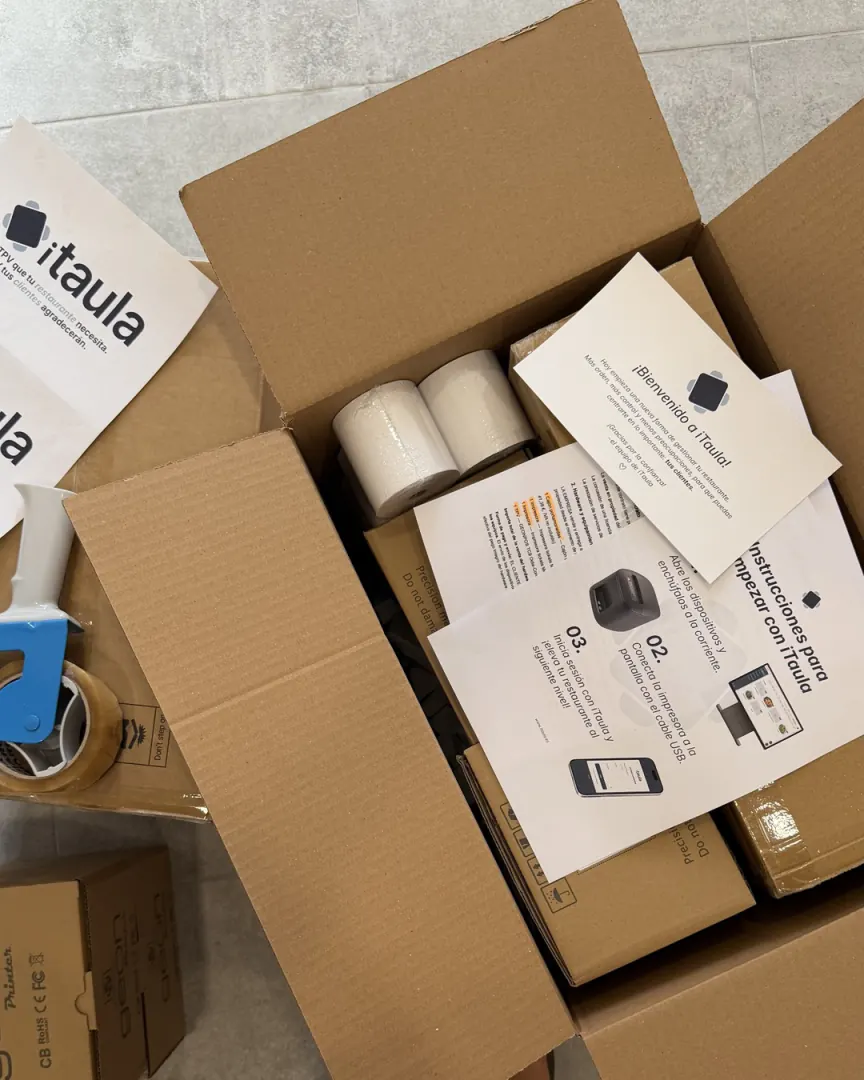 Otwarty karton iTaula z rolkami papieru, kartką powitalną i instrukcją pierwszych kroków